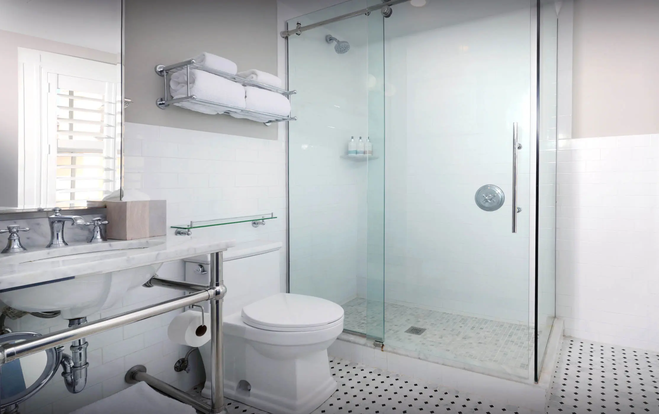 A standard bathroom with a single sink, stand up shower and toilet.